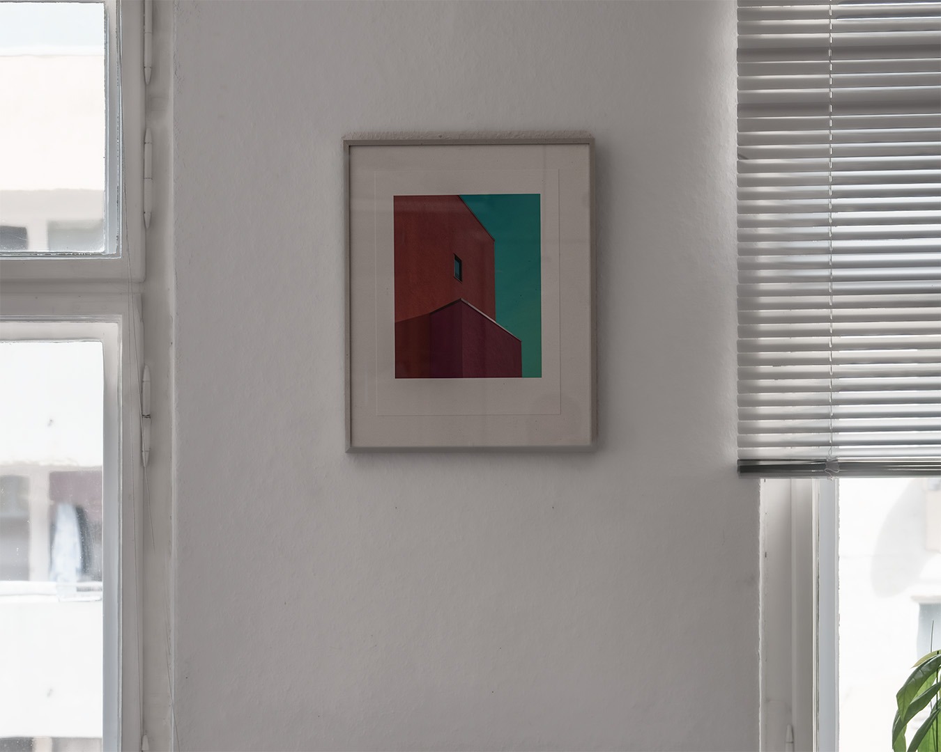 A 30 by 40 cm limited edition photograph by Jan Madeus, framed with a wide white mount, hanging on a white wall between two windows in a Berlin flat